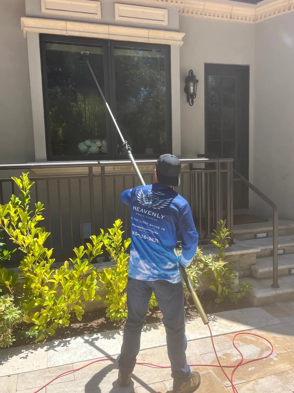 Heavenly Window Cleaning technician reaching exterior glass from the ground with a water-fed pole