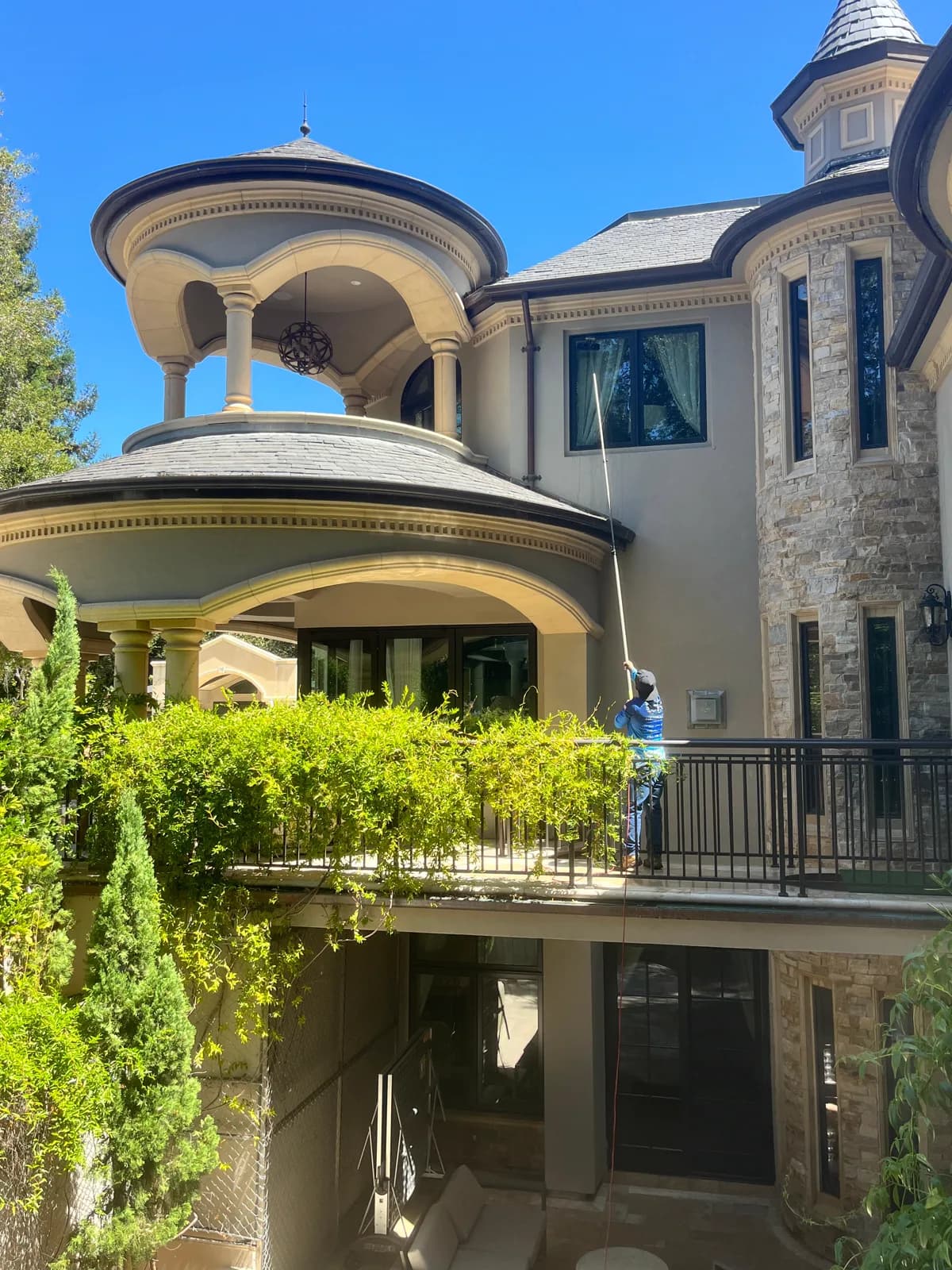 Heavenly Window Cleaning technician using a water-fed pole on upper-story windows